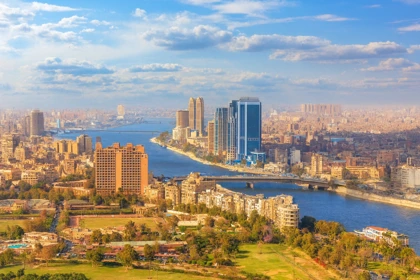 Aerial view of Cairo with the Nile River, modern skyscrapers, and historic buildings under a blue sky