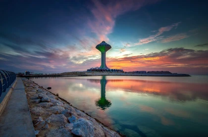Beautiful sunrise view at Dammam Al Khobar Corniche with the Water Tower reflecting on calm waters