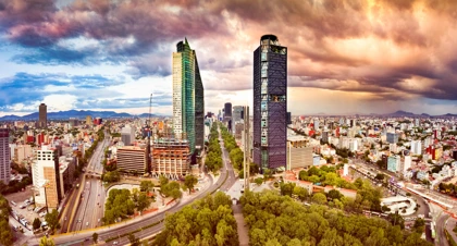 Skyline of Mexico City with skyscrapers along Paseo de la Reforma under a dramatic sunset sky