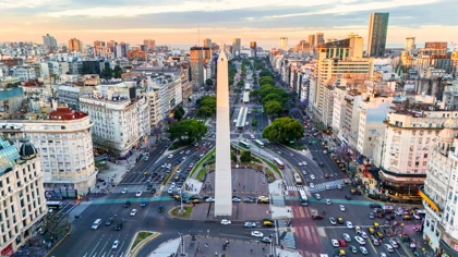 Aerial view of Buenos Aires' Obelisk surrounded by busy roads and city buildings at sunset