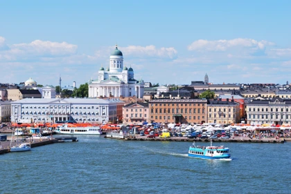 Helsinki Cathedral overlooking the bustling Market Square and harbor with a ferry on the water.