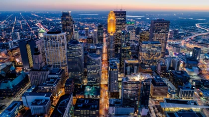 Aerial view of Minneapolis skyline at dusk with illuminated skyscrapers and city lights