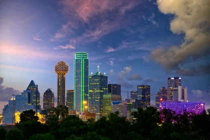 Nighttime skyline of Dallas, Texas, featuring the illuminated Reunion Tower and vibrant skyscrapers against a twilight sky