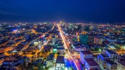 Nighttime aerial view of Phnom Penh, Cambodia, featuring illuminated city streets and modern buildings