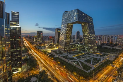 Beijing skyline at dusk featuring the illuminated CCTV Headquarters building and busy city roads