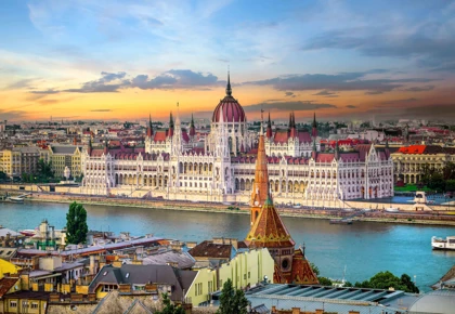 View of the Hungarian Parliament Building in Budapest, Hungary, with the Danube River in the foreground at sunset