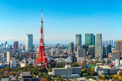 Tokyo skyline featuring the iconic red Tokyo Tower surrounded by modern skyscrapers under a clear blue sky