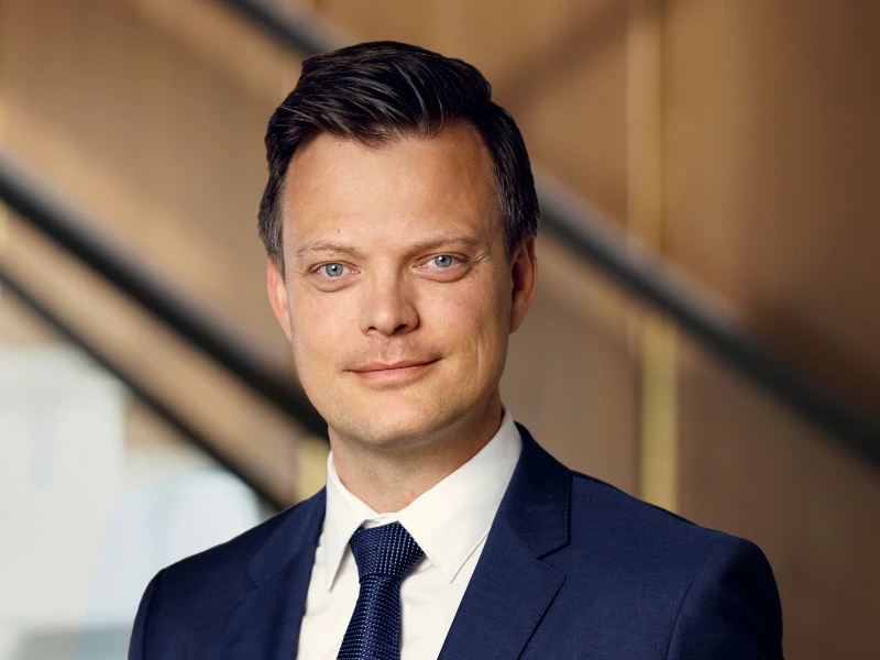 Henrik H.K. Christensen in a professional portrait, wearing a dark suit and tie, with a confident expression