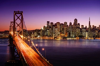 San Francisco skyline at night with the illuminated Bay Bridge in the foreground