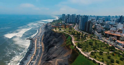 Coastal view of Lima, Peru, showing the cliffs of Miraflores, a seaside park, and modern high-rise buildings overlooking the Pacific Ocean