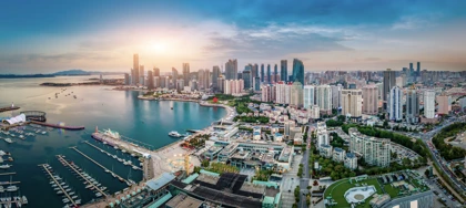 Qingdao skyline with modern skyscrapers, a coastal harbor, and a marina at sunset