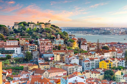 Scenic view of Lisbon, Portugal, featuring São Jorge Castle atop a hill, colorful buildings, and the Tagus River