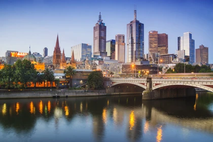 Melbourne city skyline at dusk with a bridge over the Yarra River reflecting city lights