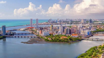 Panoramic view of Recife, Brazil, showing high-rise buildings, bridges, and waterways along the coastline
