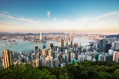 Hong Kong skyline with skyscrapers, Victoria Harbour, and surrounding mountains at sunset