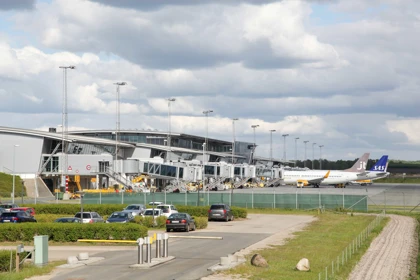 Billund Airport terminal with parked airplanes from SAS and Jettime, connected to jet bridges under a cloudy sky