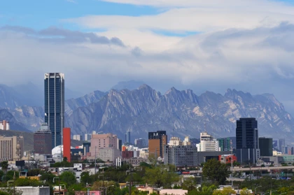 Monterrey skyline with the iconic Cerro de la Silla mountain range in the background under a cloudy sky