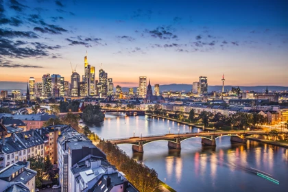 Night view of Frankfurt, Germany, featuring illuminated skyscrapers, the Main River, and city bridges