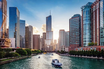 Chicago skyline with the Trump Tower overlooking the Chicago River, featuring boats and modern high-rise buildings at sunset