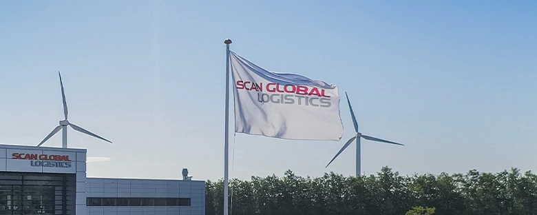 Scan Global Logistics flag waving outside the headquarters at Jernholmen 49, Hvidovre, with wind turbines and a clear blue sky in the background
