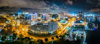 Norfolk, Virginia skyline at night with illuminated buildings, streets, and a waterfront marina