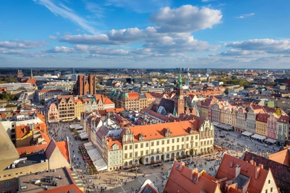 Colorful historic buildings surround the Market Square in Wrocław, Poland, under a bright blue sky