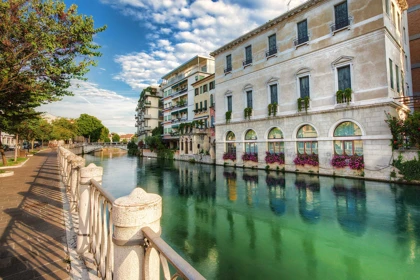 Scenic canal view in Treviso, Italy, with colorful flowers, historic buildings, and a serene water reflection