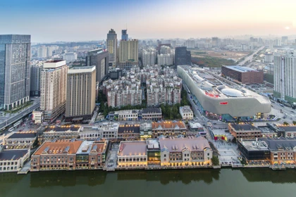 Wuhan cityscape with modern high-rise buildings, a large shopping complex, and riverside architecture at sunset