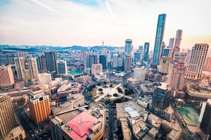 Dalian city skyline featuring modern skyscrapers and a central circular plaza at sunset