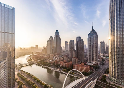 Tianjin skyline at sunrise featuring modern skyscrapers, a river, and an elegant bridge