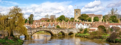Stone bridge over the River Medway in Aylesford, Kent, with historic cottages and a church tower in the background