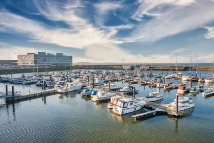 Esbjerg Marina in Denmark with boats docked in calm waters and a modern building in the background under a clear sky