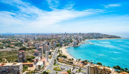 Aerial view of Alicante's coastline with sandy beaches, turquoise waters, and city skyline under a clear sky