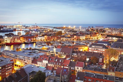 Evening aerial view of Dunkirk, France, featuring illuminated harbor, boats, and city buildings