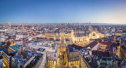 Panoramic evening view of Milan, showcasing the illuminated Milan Cathedral (Duomo di Milano) and surrounding cityscape